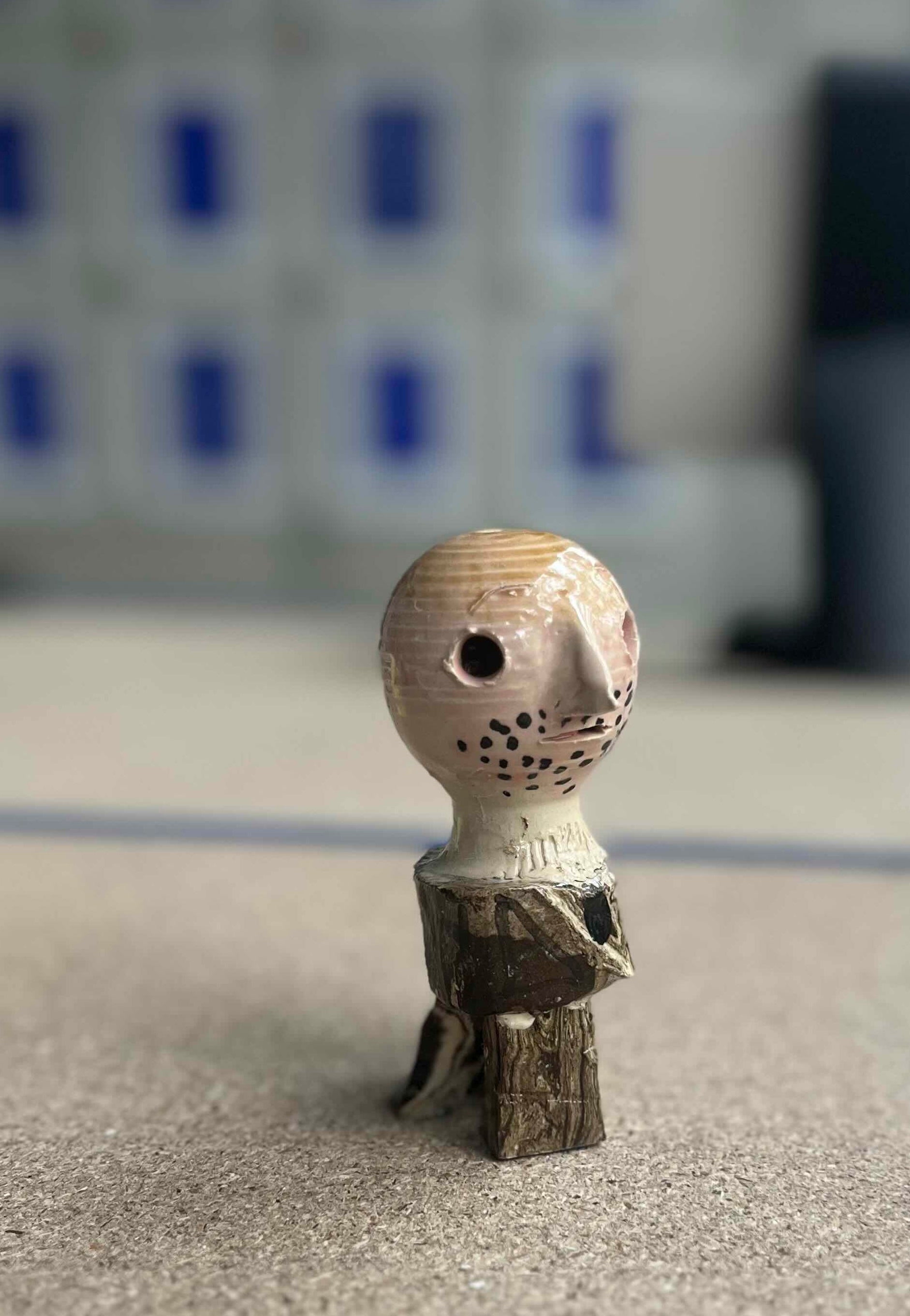Kleinformatige Keramikskulptur „Knut“ des Künstlerduos 44flavours. Es handelt sich um eine kleine Figur in Brauntönen mit kahlem Kopf, spitzer Nase und Dreitagebart