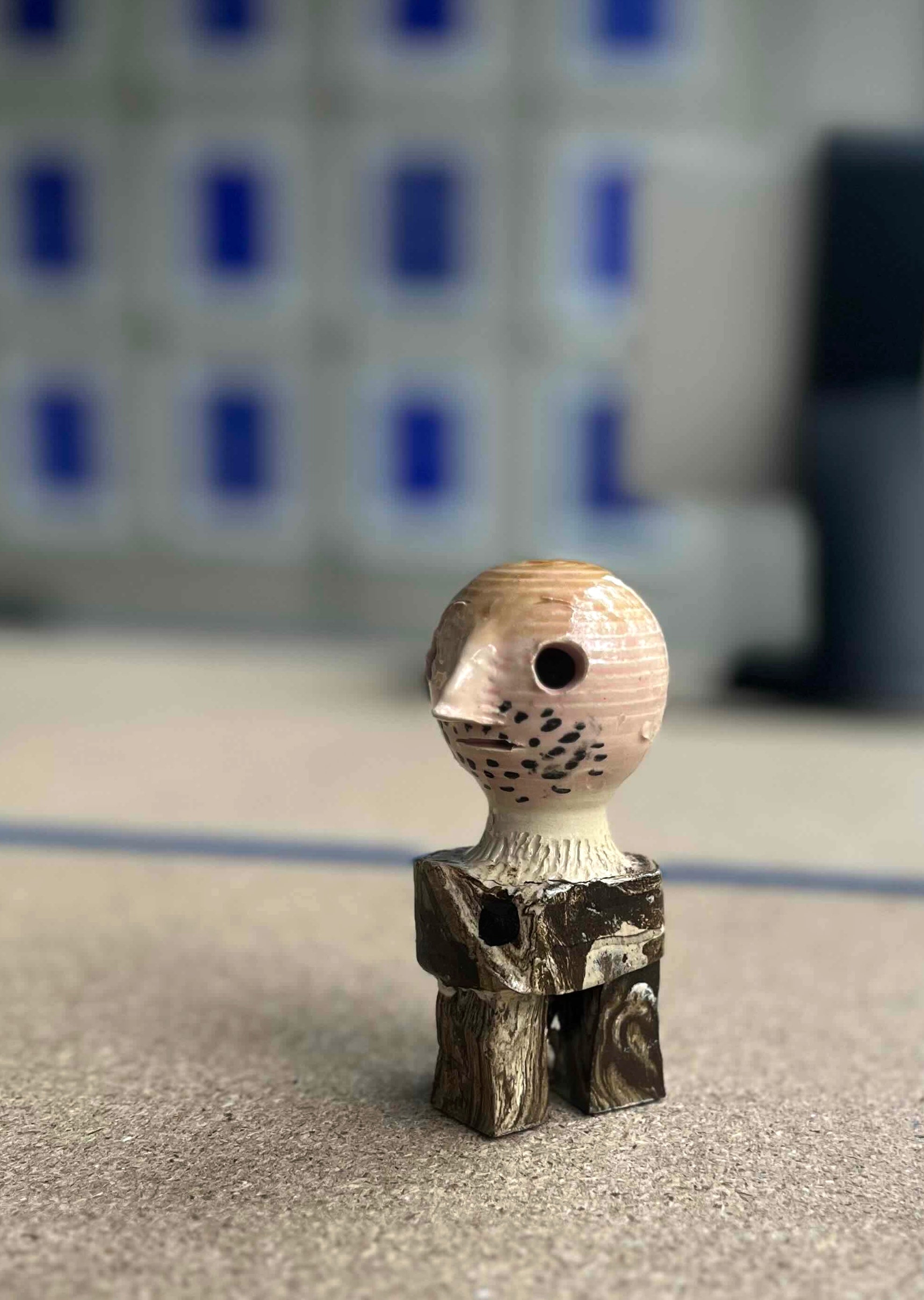Kleinformatige Keramikskulptur „Knut“ des Künstlerduos 44flavours. Es handelt sich um eine kleine Figur in Brauntönen mit kahlem Kopf, spitzer Nase und Dreitagebart