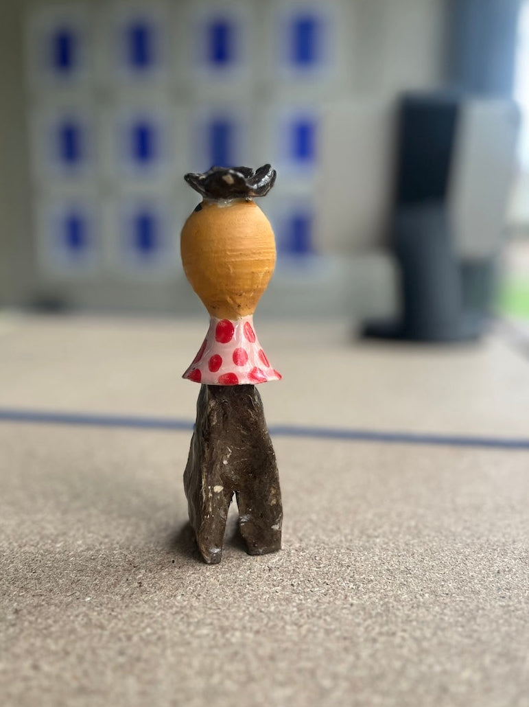 Kleinformatige Keramikskulptur „Salvador“ des Künstlerduos 44flavours, hier von hinten zu sehen. Es handelt sich um eine kleine Figur in mit kessem  Hütchen, rot gepunktetem Oberteil und brauner Hose.