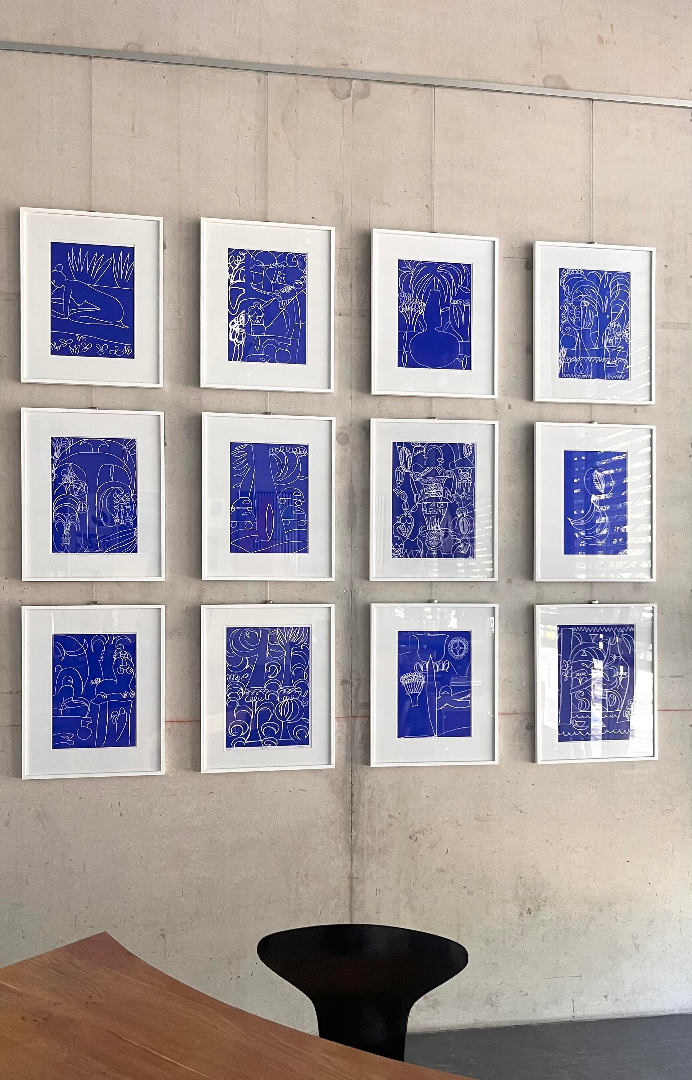 Installationsansicht der sogenannten „Blauen Serie“, einer Gruppe von Siebdrucken von Simon Blume. Hier hängen insgesamt 12 Motive vor einer Sichtbetonwand, alle weiß gerahmt mit Passepartout. 