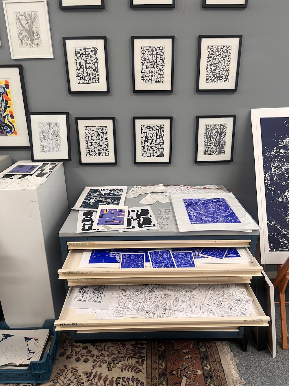 Blick ins Atelier des Künstlers Simon Blume. In den offenen Schubladen eines Grafikschrankes und an der Wand sind Druckgrafiken zu sehen. 